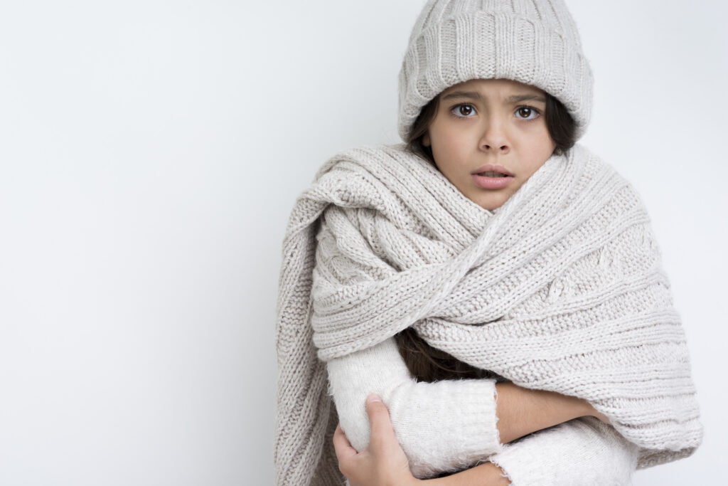 Shivering girl in winter wear, illustrating why proper HVAC system sizing matters for long-term home comfort.