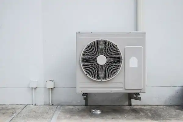 Outdoor heat pump unit mounted against a home exterior
